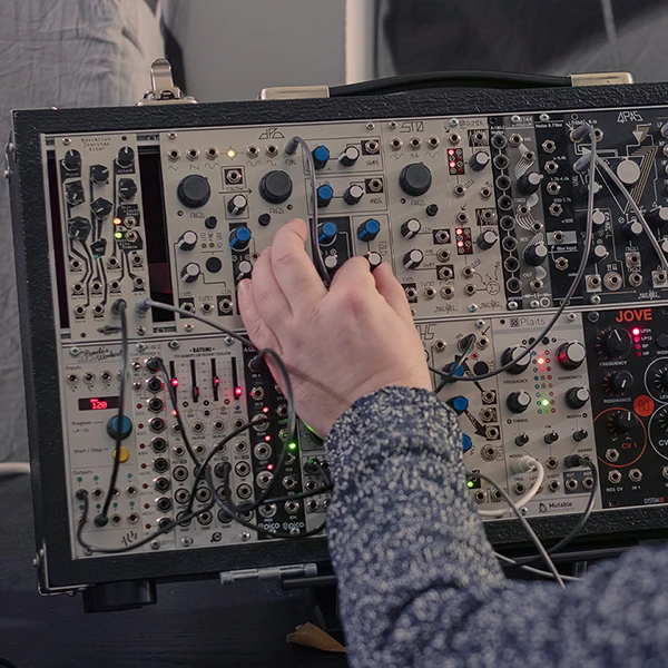 a hand on a modular synthesizer
